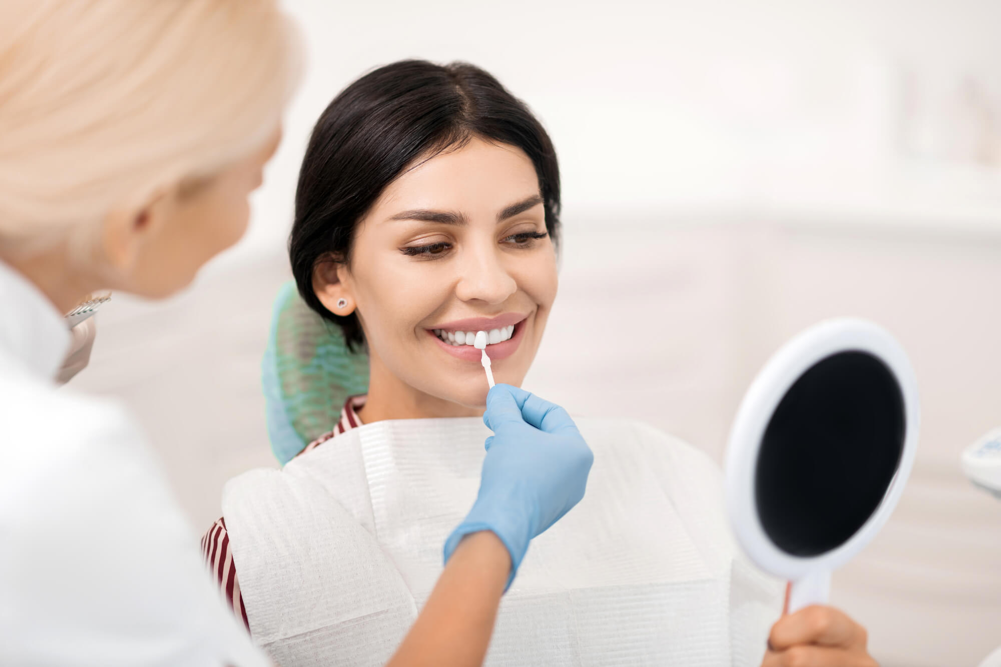 a woman choosing the right tooth shade before getting professional Teeth Whitening in Coral Gables